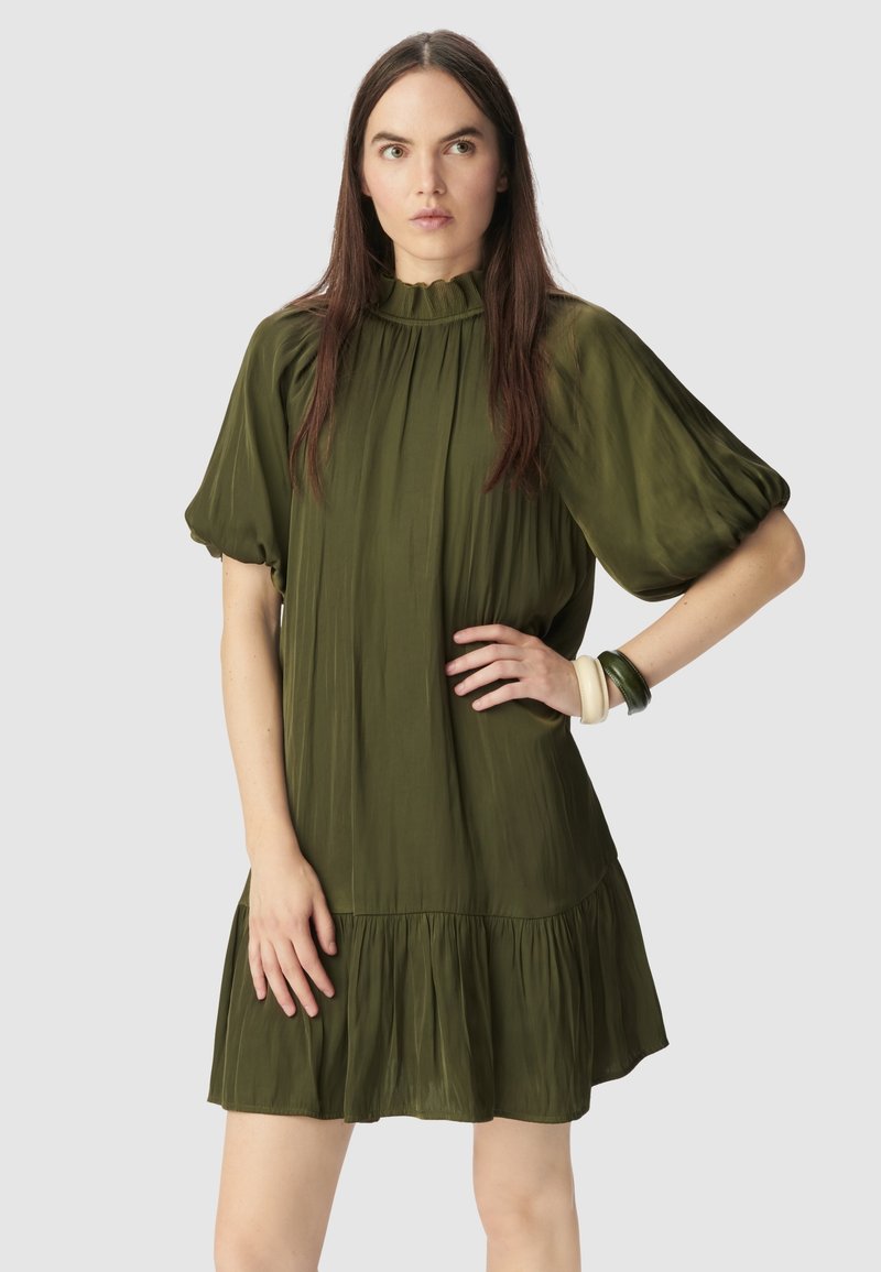 Vestido corto de manga corta en verde oliva con un cuello alto y arrugado, corte relajado y dobladillo fruncido. Textura suave, hasta la rodilla y diseño minimalista.