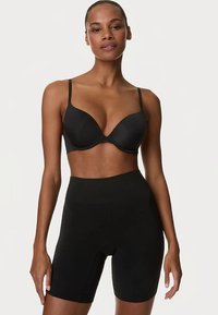 Sujetador moldeado negro con copas y tirantes ajustables, combinado con pantalones cortos negros de talle alto. Ambos artículos presentan una textura suave y un diseño sin costuras.