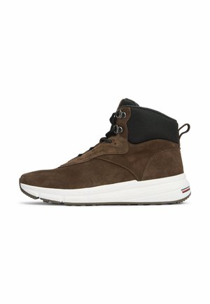 Bruine suède hoge sneaker met zwarte enkelkraag, zwarte veters, dikke witte zool en trekstrikje aan de hiel, gezien vanaf de zijkant.