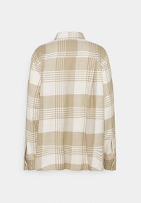 Chemise à manches longues beige et blanche à carreaux avec poignets boutonnés et ourlet droit, montrée de dos sur un fond uni.