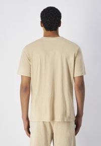 Beige katoenen t-shirt met korte mouwen, een ronde hals en een ontspannen pasvorm, met een zachte textuur en minimale steekdetails.