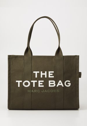 Oliven grønn stoff tote bag med doble håndtak. Har stor hvit tekst som sier "THE TOTE BAG" og mindre tekst "MARC JACOBS" under.