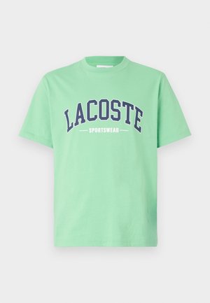 Zelené bavlněné tričko s kulatým výstřihem. Na hrudi se nachází výrazný námořnický text "LACOSTE" a "SPORTSWEAR". Krátké rukávy.