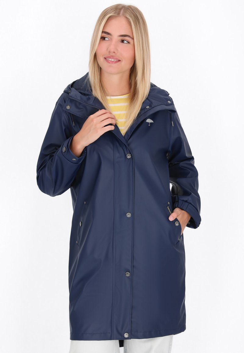 Impermeable de hombre en color navy con frente con cremallera, capucha ajustable y botones de presión. Cuenta con bolsillos laterales y un discreto detalle de logo.