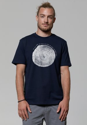 Navy blue cotton T-shirt featuring a white tree ring graphic and text above. Short sleeves and a relaxed fit. Soft texture.