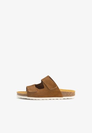 Bruine suède slipper met twee verstelbare klittenbandsluitingen, kurken voetbed en witte geribbelde rubberen zool, zijaanzicht.