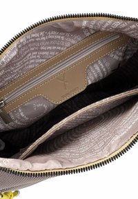 Interno di una borsa marrone con zip, caratterizzato da fodera beige, una tasca con zip e un motivo di testo ripetuto. Tessuto testurizzato con cuciture resistenti.