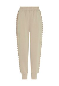 Beżowe dresy z elastycznym pasem, ozdobione falistym wykończeniem po bokach i zwężanymi ściągaczami przy kostkach. Miękka tekstura.