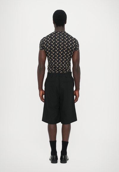 Black shorts with a relaxed fit, paired with a fitted black top featuring a repeating cream crescent moon pattern.