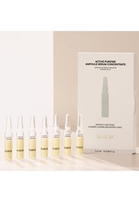 Das Babor Active Purifier Ampullen-Serum-Set enthält sieben klare Glasampullen mit gelbem Serum, verpackt in einer eleganten weißen Schachtel mit schwarzem Text.