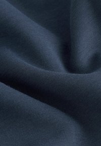 Țesătură întunecată de culoare navy, cu o textură netedă, tricotată fin, care prezintă drapaje delicate cu linii de cusătură vizibile ce creează modele subtile.