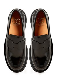 Zwarte gepolijste leren loafers met een ronde neus, duidelijke stiksels en een decoratieve band over de wreef. Gouden reliëf branding aan de binnenkant.