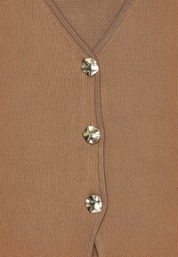 Lysebrunt strikket cardigan med V-hals og tre dekorative metallknapper foran. Glat tekstur, afslappet design.