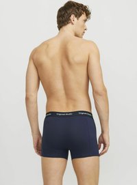 Dunkelblaue, figurbetonte Boxershorts mit einem schwarzen Bund, auf dem "Originals Studio" steht. Glatte Textur und ein aerodynamisches Design. Von hinten gezeigt.