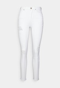 Jeans skinny de denim branco com remendos desgastados, bainhas desfiadas e design tradicional de cinco bolsos. Apresenta um fecho de botão e passantes para cinto.