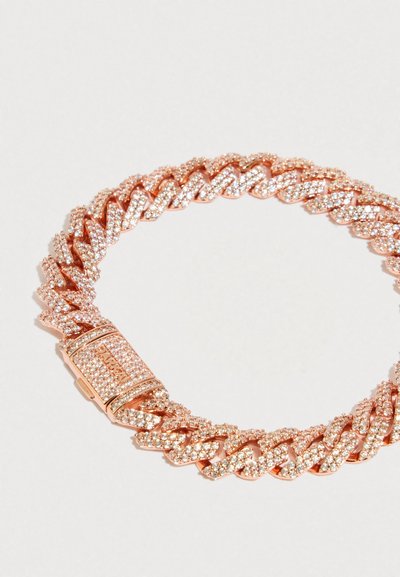 Náramek z růžového zlata s pavé krystaly a obdélníkovou sponou vyrytým nápisem "DYLAN" na bílém pozadí.