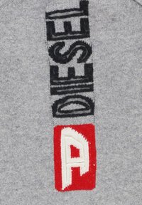 Felpa grigia a maglia con grande testo nero "DIESEL" e una toppa rossa e bianca con la lettera "A". Il materiale sembra morbido con una finitura testurizzata.