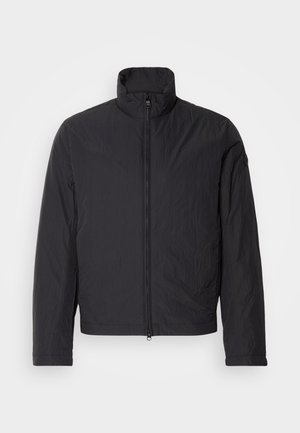 Giacca leggera nera con colletto alto, zip frontale e maniche lunghe. Realizzata in tessuto stropicciato, ha un design minimalista.