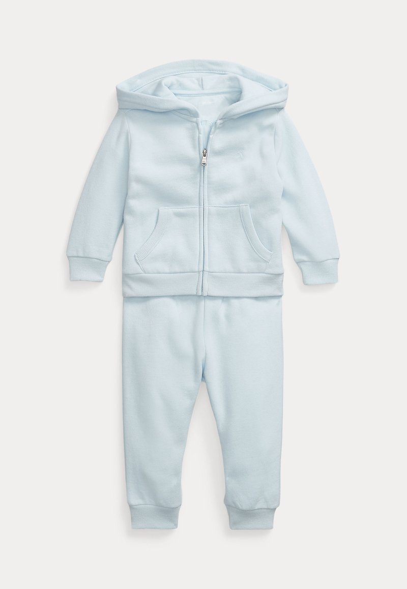 Απαλή μπλε φούτερ φόρμα με καπό, κατασκευασμένη από μαλακό βαμβάκι. Διαθέτει μπροστινό φερμουάρ, δύο μπροστινές τσέπες και ριμπ μανσέτες και στρίφωμα. Λείο υλικό.