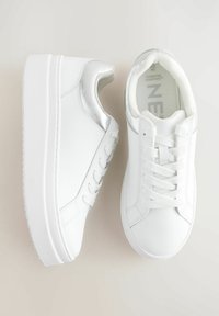 Sneaker bianche con tomaia in sintetico liscio, caratterizzate da un accento argento, suola spessa e lacci piatti. Punta arrotondata e dettagli di cucitura minimi.