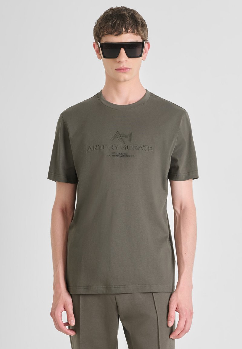 Camiseta de algodón verde oliva con mangas cortas, escote redondeado y logo en relieve "ANTONY MORATO" en el frente. Textura suave.