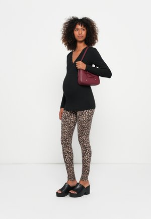 Graviditetsantrekk med en svart topp med blondekant, leopardmønstrede leggings og en burgunder crossover-veske. Svart plattformklosser fullfører antrekket.