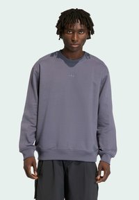 Szara bluza z długimi rękawami i prążkowanymi mankietami, posiadająca okrągły dekolt oraz subtelne logo na piersi; gładka tekstura i luźny fason.