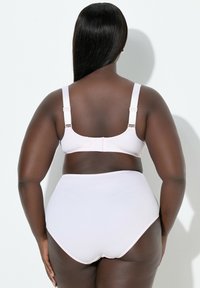 Sujetador inalámbrico de color rosa claro con tirantes ajustables y bordes festoneados, combinado con bragas a juego de talle alto, ambos en tejido elástico.