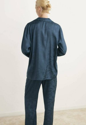 Conjunto de dos piezas de satén azul marino que incluye una camisa de botones de manga larga con cuello y pantalones a juego con un sutil patrón floral.