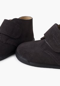 Scarpe per bambini in suede grigio scuro con strap in Velcro, punta arrotondata e suola in gomma con texture antiscivolo. Dettagli cuciti sui lati.