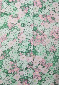 Chemise en coton avec un fond vert et un motif floral en rose, blanc et vert. Comprend des boutons le long de la couture avant.