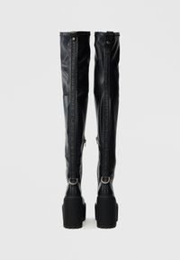 Čierne čižmy nad kolená z hladkej umelej kože, s hrubou platformovou podrážkou, zapínaním na zips a pásikmi zdobenými logom.