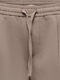 Pantalon marron clair avec une ceinture élastique et un cordon en tissu noué au centre devant.