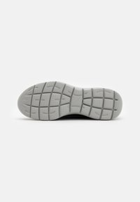 Suela de zapato de goma gris con un patrón texturizado. Presenta secciones elevadas para mejorar el agarre y la durabilidad, con un diseño de punta redondeada.
