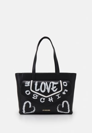 Sort Moschino tote taske med hvid graffiti-tekst og hjerte-design, med to skulderstropper og en frontklap.