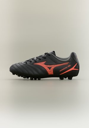Schwarzer Fußballschuh mit roten Akzenten, Stollen an der Sohle und "Monarcida Neo" Text an der Außenseite, aus dem Außenprofil betrachtet.