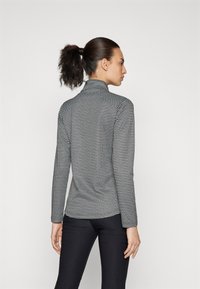 Hosszú ujjú, testhezálló garbó felső fekete-fehér kutyafog mintában, sima, rugalmas textúrával és magas gallérral.