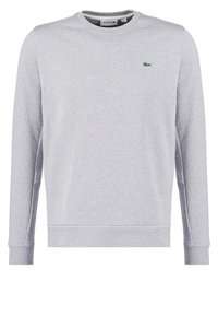Sudadera de cuello redondo de manga larga en gris claro con un pequeño logo de cocodrilo verde de Lacoste en el lado izquierdo del pecho.