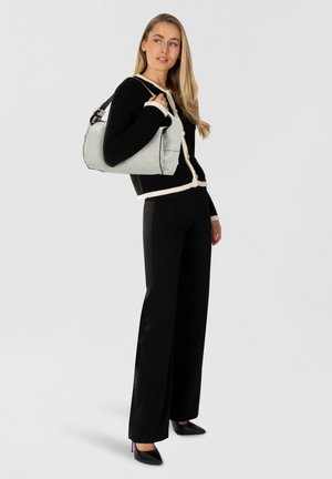 Borsa grigia con finitura testurizzata, cardigan nero a maglia con rifiniture avorio, pantaloni neri larghi e décolleté neri a punta su uno sfondo neutro.