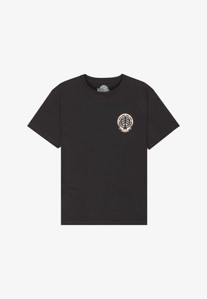 Musta puuvillainen t-paita, jossa on lehtilogolla rintakehässä, yhdistetty väljiin vaaleansinisiiin farkkuihin ja mustiin matalavartisiin tennareihin.