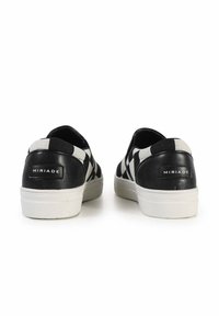 Scarpe slip-on a scacchi bianco e nero con tallone in pelle liscia, tomaia in tessuto testurizzato e suola in gomma bianca. Logo del brand visibile sul tallone.