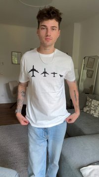 White cotton t-shirt featuring black silhouettes of four airplanes, varying in size, positioned above the waist. Relaxed fit with short sleeves.