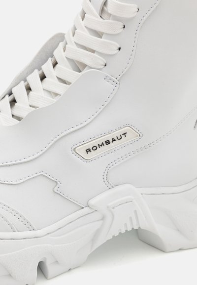 White high-top sneaker made of smooth leather with textured accents, thick sole, and a branded label. Features classic lace-up design.
