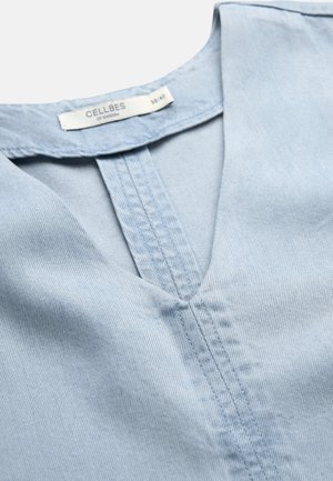 Lichtblauw denim kledingstuk met V-hals-zoomstiksels en Cellbes of Sweden label in maat 38/40 aan de binnenkant van de kraag.