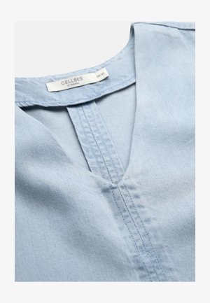 Lichtblauw denim kledingstuk met V-hals-zoomstiksels en Cellbes of Sweden label in maat 38/40 aan de binnenkant van de kraag.