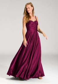 Un abito in satin bordeaux lungo fino al pavimento, con un corpetto arricciato, spalline decorate e tessuto testurizzato che scorre in una delicata silhouette a A.