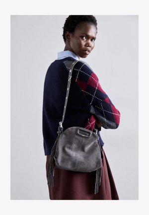 Borsa in suede grigio con fondo arrotondato, dettagli in pelle e frange. La tracolla presenta hardware metallico ed è regolabile.