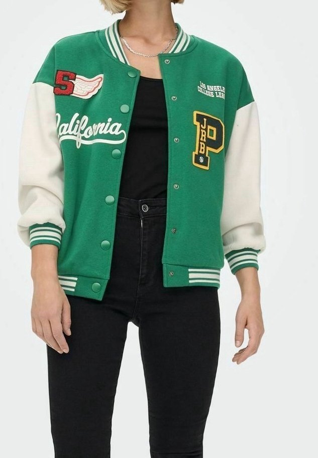Personne portant une veste universitaire verte et blanche avec les inscriptions "California" et des écussons de lettres, sur un t-shirt noir et un pantalon noir, visible du cou jusqu'aux hanches.