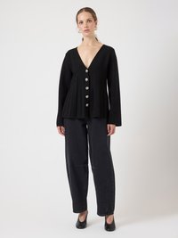 Black cardigan with a V-neck, pleated design, and six silver buttons. Paired with dark jeans and black pumps for a monochromatic look.