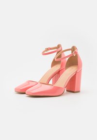 Scarpe con tacco alto in pelle verniciata rosa, con punta quadrata, cinturino alla caviglia e tacco a blocco. Texture liscia, colore solido e dettagli di design minimi.